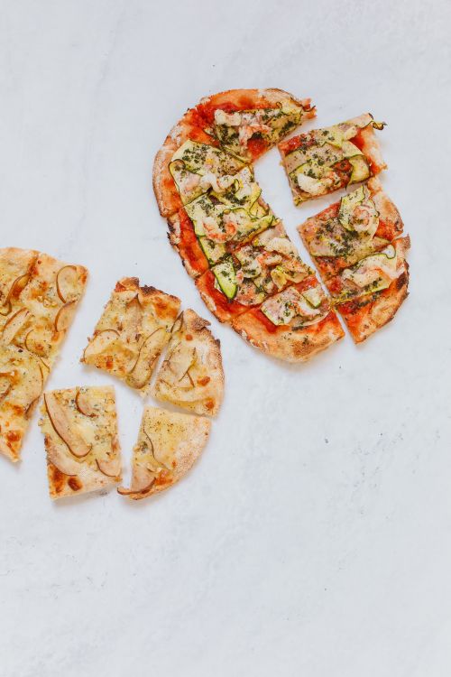 Pizzas cortadas sobre uma superfície clara, fotografia ilustrativa